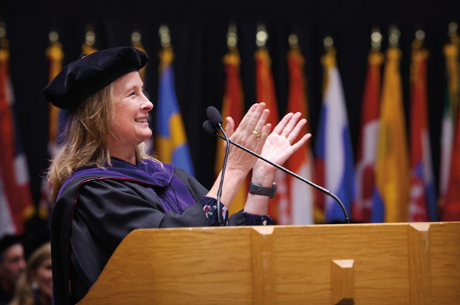 Kate Adams wearing graduation cap and gown and smiling and clappig